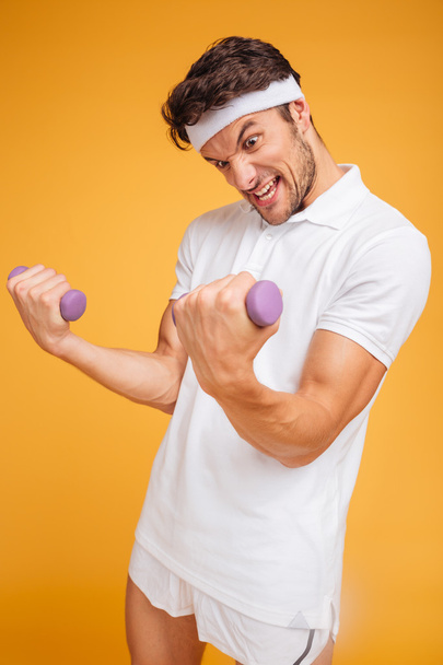 Fitness man doing exercises and lifting two heavy small dumbbells - Photo, image