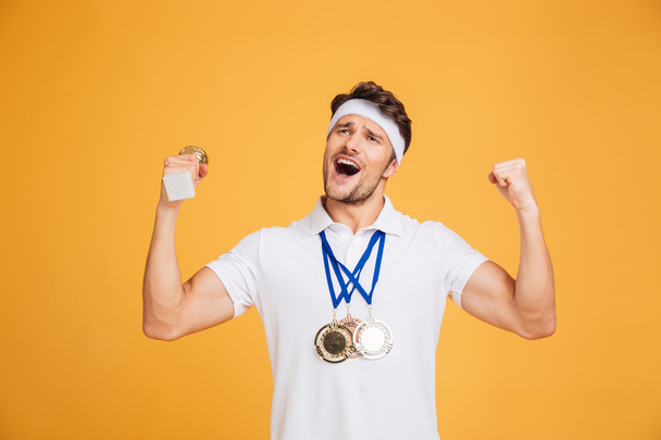 Exitoso deportista con tres medallas gritando y celebrando la victoria
 - Foto, imagen