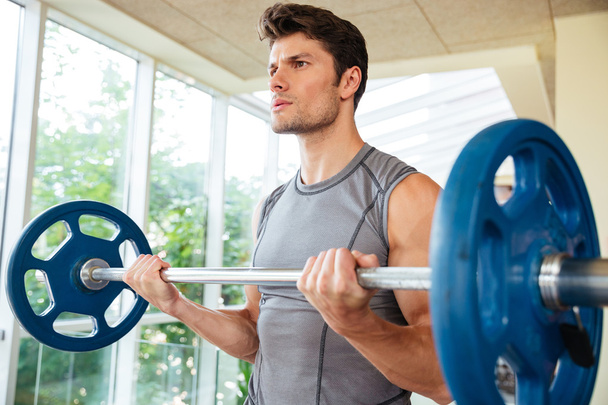 Fitness man lifting barbell in gym - Фото, изображение