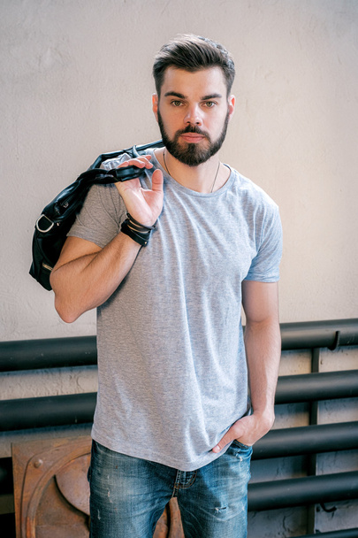 Portrait of good-looking young stylish man with handbag posing at camera - Fotografie, Obrázek