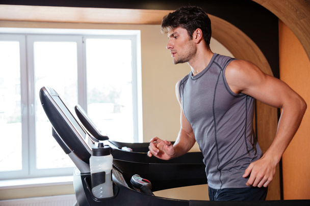 Man athlete warming up and running in treadmill in gym - Foto, Bild