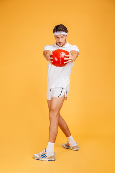 Full length of serious sports man exercising with red ball - Photo, image