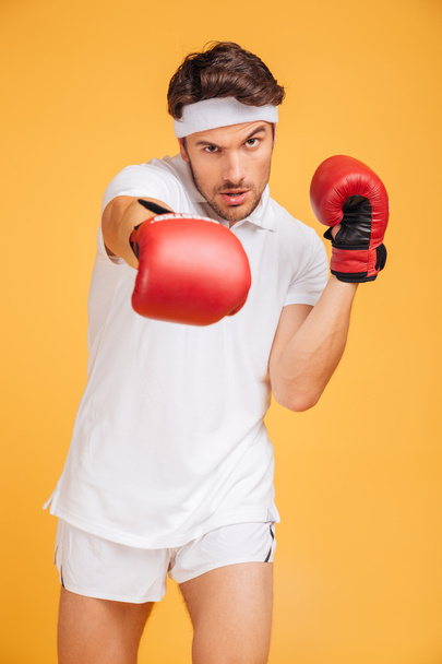 Handsome young man boxer in red gloves standing and boxing - Foto, afbeelding