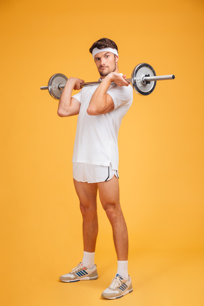 Playful young sportsman holding barbell and making funny face - Photo, Image