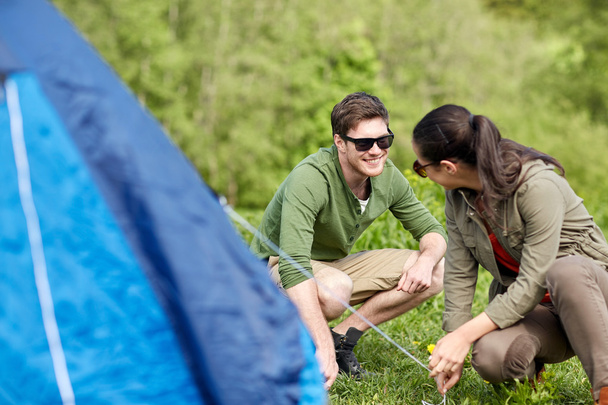 happy couple setting up tent outdoors - Foto, imagen