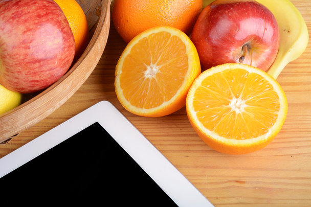 Fruits and a Tablet PC on wooden table. - Photo, image