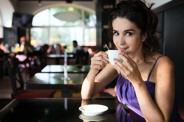Aantrekkelijke vrouw koffie drinken in een café - Foto, afbeelding
