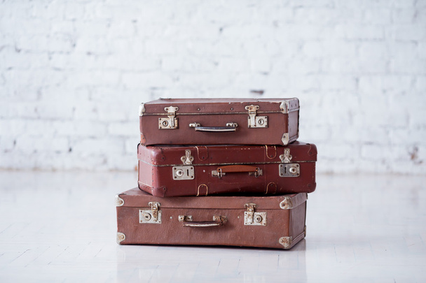 Stack of three brown retro suitcases on white floor - Фото, зображення