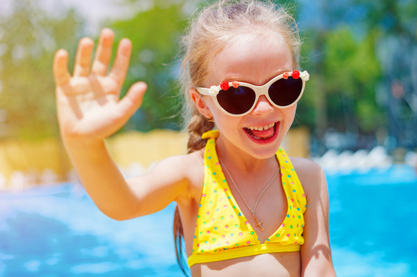 little girl in sunglasses near the pool waving and smiling - Fotoğraf, Görsel