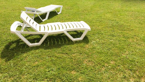 weiße Liegestühle auf grünem Rasen  - Foto, Bild