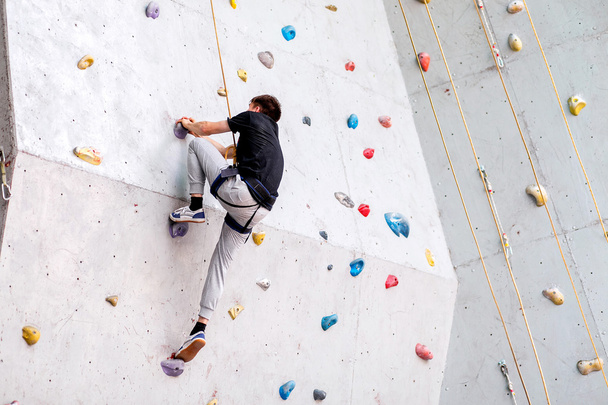 man climbing on artificial boulders wall indoor, rear view - Photo, Image