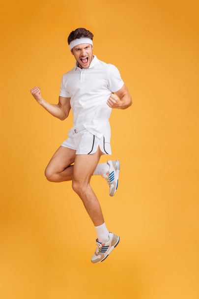 Happy handsome young sportsman shouting and jumping in the air - Фото, изображение
