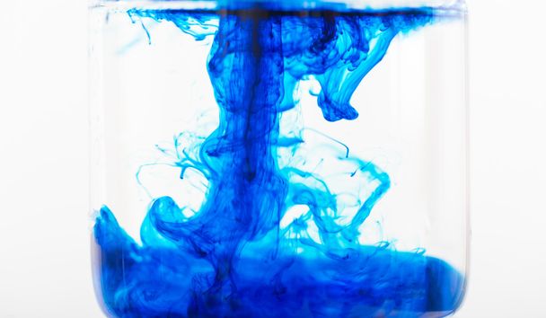 Ink soft on blue water in a glassware. - 写真・画像