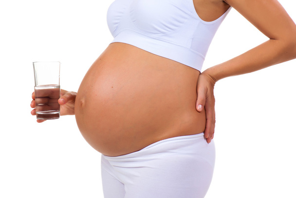 Close-up of belly of a pregnant woman and glass of water - Foto, immagini