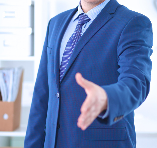 Business and office concept - handsome businessman with open hand ready for handshake - Foto, afbeelding
