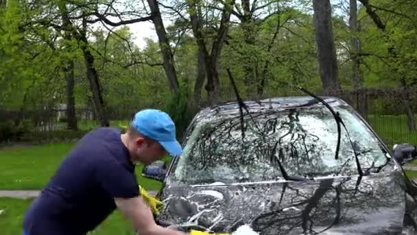 Mannelijke werknemer wassen auto in open lucht. Handheld schot. - Video
