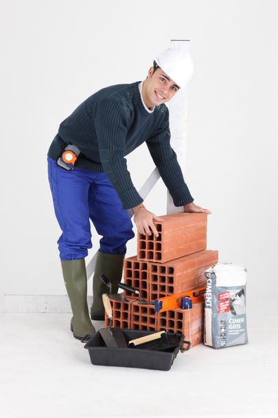 A bricklayer posing with his tools and building materials - Valokuva, kuva