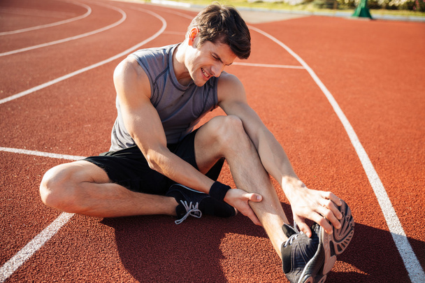 Young male runner suffering from leg cramp on the track - Φωτογραφία, εικόνα