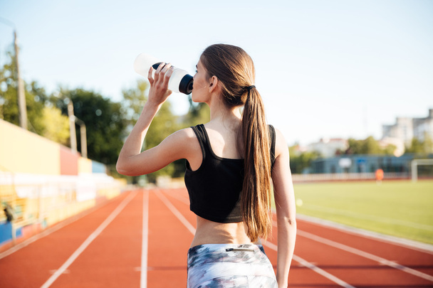 Young female athlete drinking from water bottle after workout outdoors - Foto, Imagem