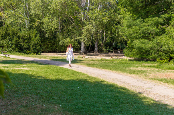 женщина в сандалиях на высоких каблуках гуляет по парку
 - Фото, изображение