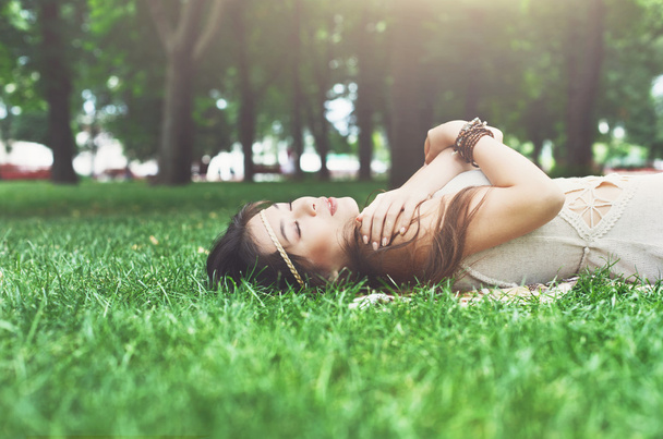 Красива молода дівчина лежить на траві в літньому парку
 - Фото, зображення