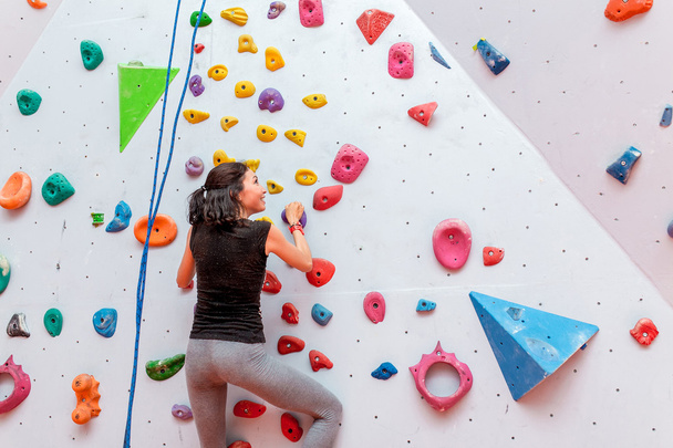 Athletic woman climbing indoors, view from the back - Photo, Image