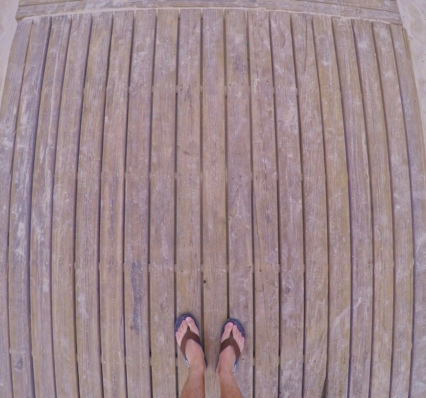 мужские ноги в шлепанцах на деревянной дорожке
 - Фото, изображение