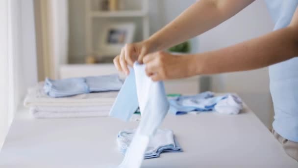 pregnant woman folding baby boys clothes at home 5 - Video