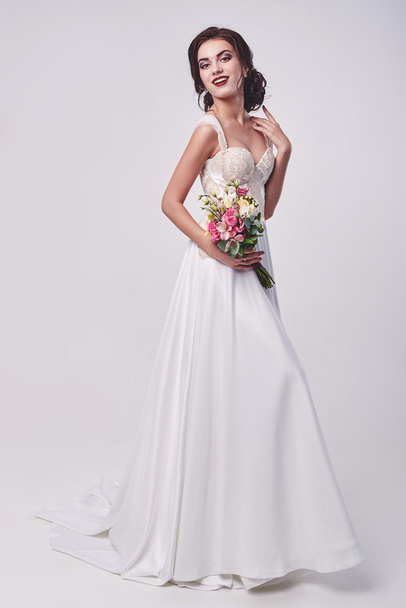Woman in wedding dress with flowers' bouquet. - 写真・画像