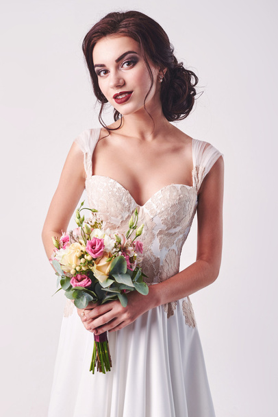 Young attractive bride with the bouquet of white roses - 写真・画像