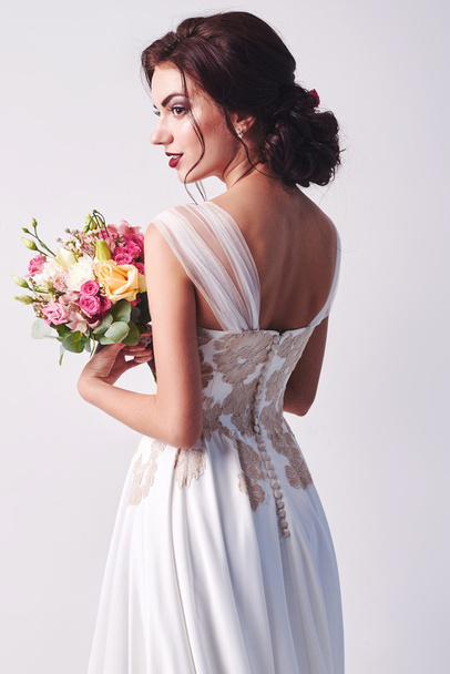 Woman in wedding dress with flowers' bouquet. - Photo, Image