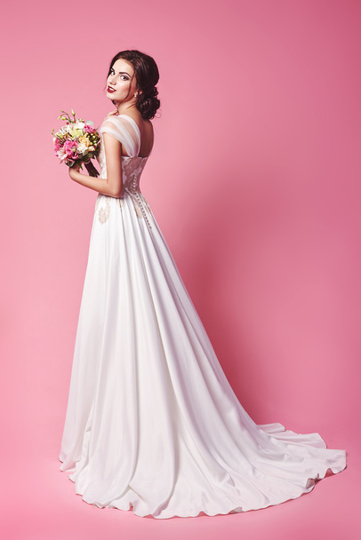 Bride.Young fashion model with perfect skin and make up, beige background, curly hair, flowers in hair - Foto, Imagen