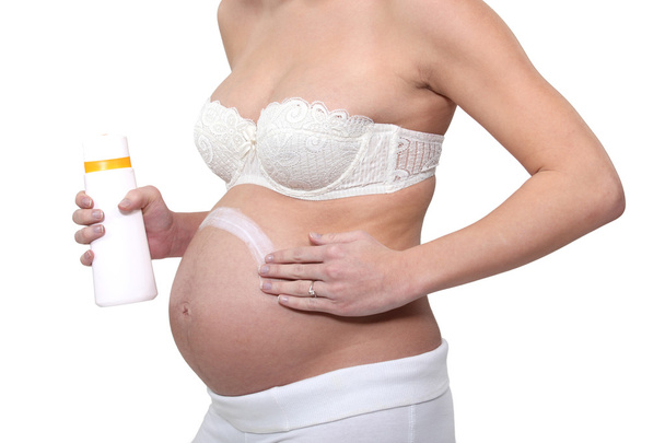 Mulher grávida colocando creme na barriga
 - Foto, Imagem