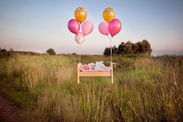 tiny baby asleep in his crib in lace bonnet A    in   in  cap and flies away with balloons - Foto, Bild