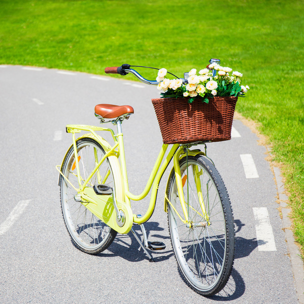 żółty rower vintage kwiaty w wiklinowym koszu - Zdjęcie, obraz