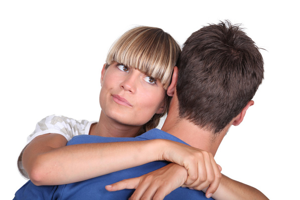 Young woman hugging her boyfriend with a look of uncertainty - Fotoğraf, Görsel