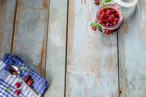 Jar of cherry jam and some cherries on the napkin - Фото, зображення