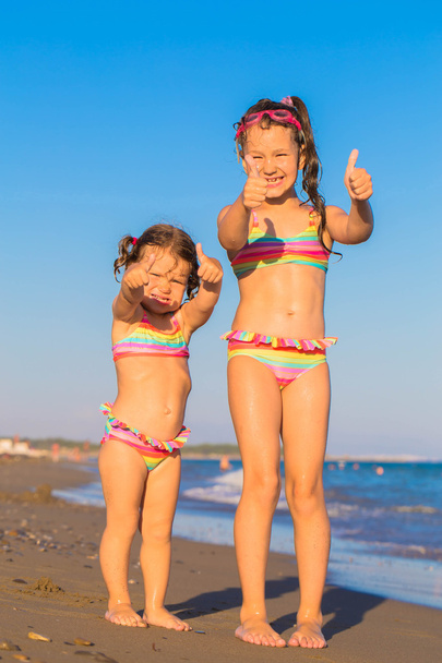 Kinderen opdagen duimen op het strand.  - Foto, afbeelding