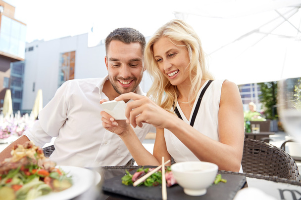 щаслива пара з смартфоном на терасі ресторану
 - Фото, зображення