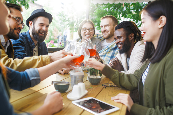 Gelukkige mensen roosteren met dranken in café - Foto, afbeelding