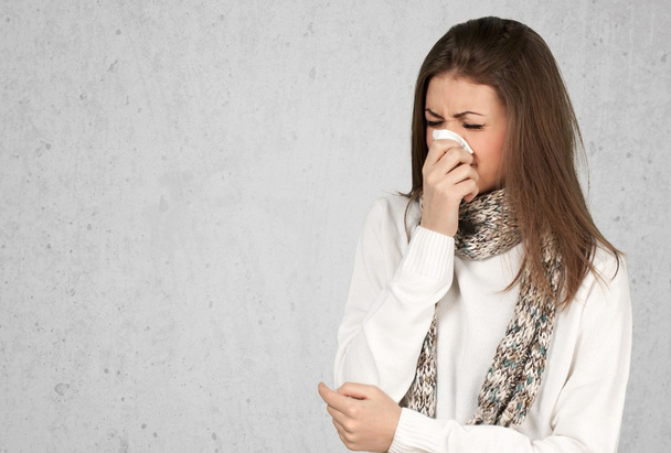  woman sneezing in a tissue  - 写真・画像