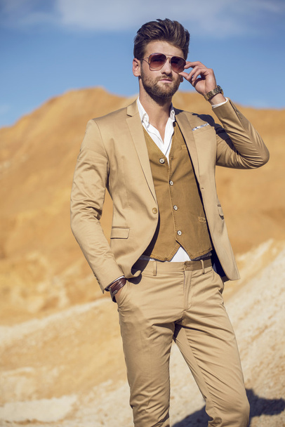 Hombre guapo elegantemente vestido caminando por el desierto
 - Foto, Imagen