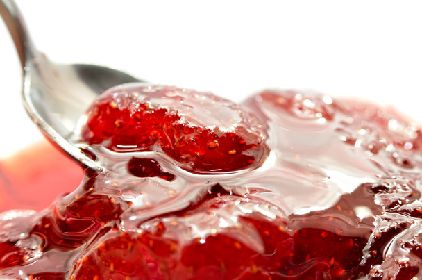 Strawberry jam is stirred with a spoon on a white background. Fruit dessert close up. Confectionery. - Foto, immagini