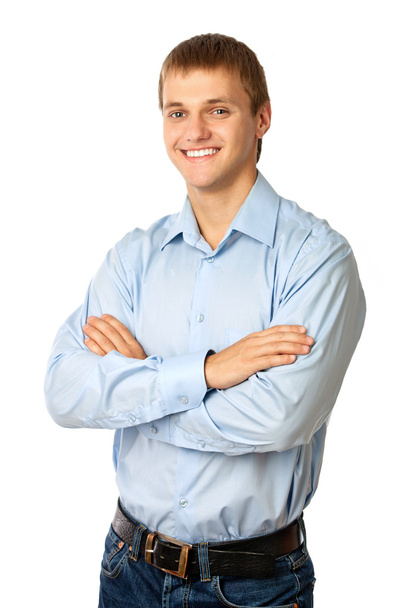 χαμογελαστός νεαρός άνδρας στέκεται με τα χέρια διπλωμένα ενάντια στο λευκό - Φωτογραφία, εικόνα