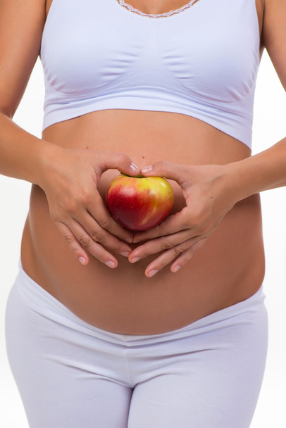 Pregnant woman holding an apple. Vitamins and healthy food during pregnancy - Photo, image