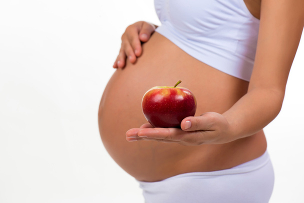 Close-up of pregnant belly and apple. Vitamins and healthy food during pregnancy - Fotoğraf, Görsel