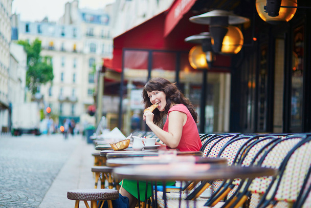 Woman drinking coffee with croissant in Parisian cafe - Фото, изображение