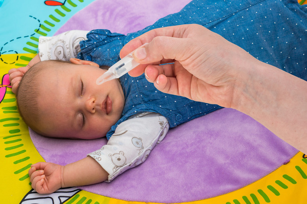 Новорожденный получает капли носа с солевым раствором
 - Фото, изображение