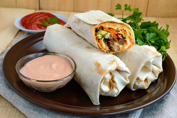 Shawarma - Oriente Medio (árabe) plato de pita (lavash) relleno con: carne a la parrilla, salsa, verduras
. - Foto, Imagen