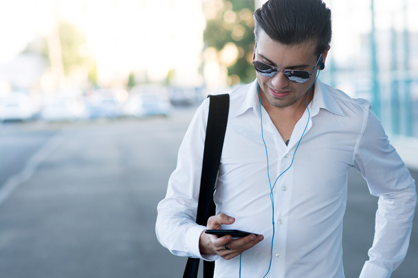 handsome young man with smartphone and headphones listen music - Foto, imagen